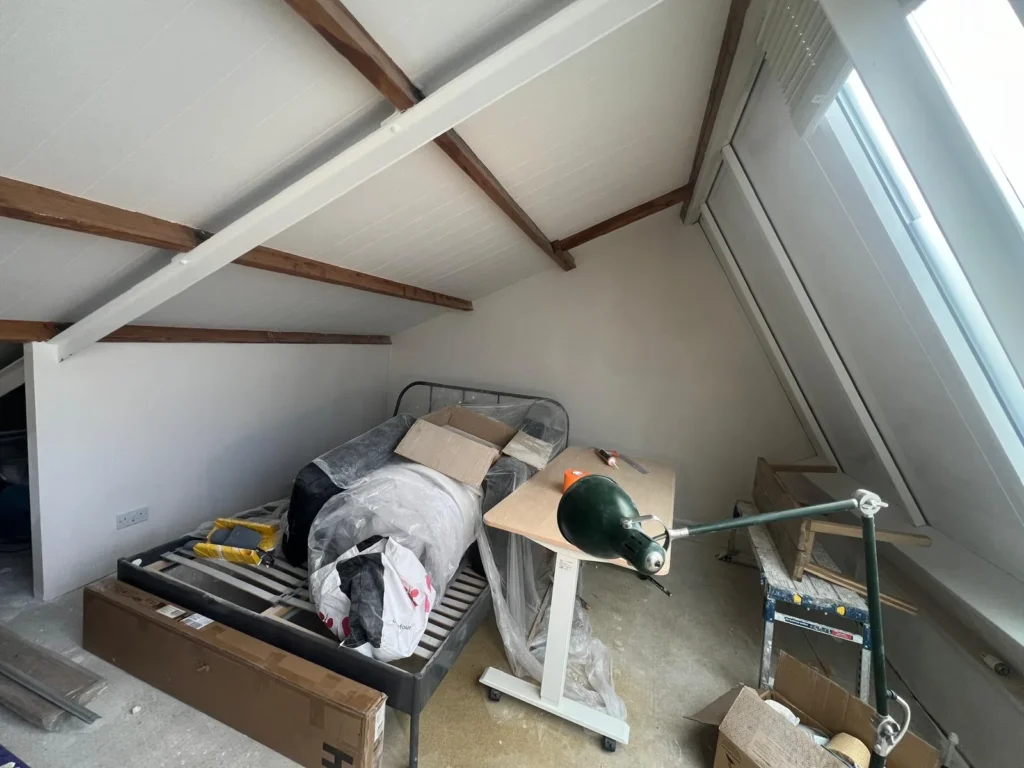 Loft bedroom with plastered walls and painted beams