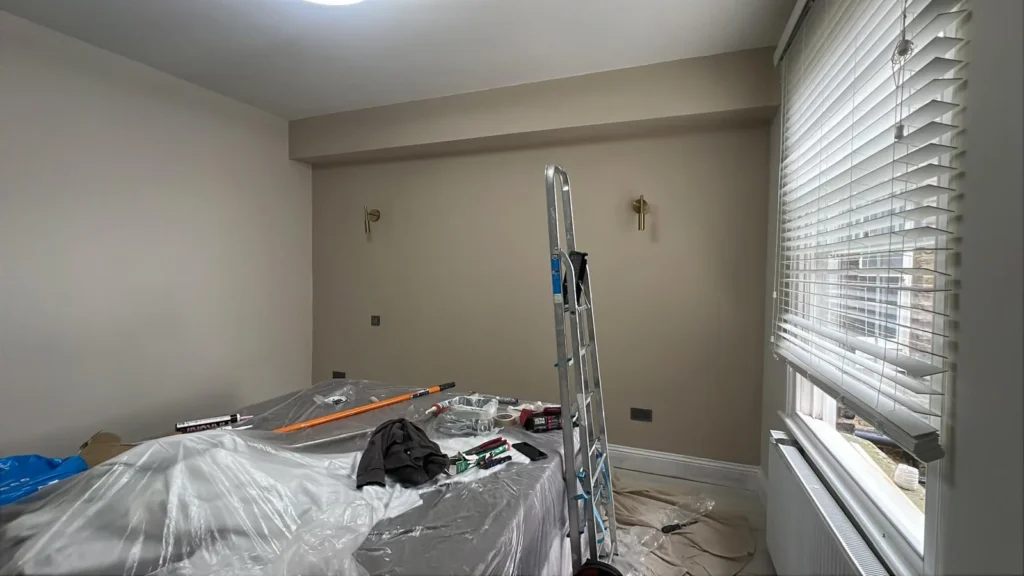 Bedroom being decorated in warm taupe with brass wall lights