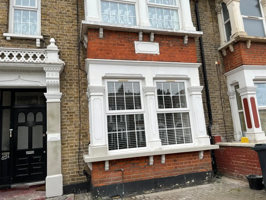 Bay window with new render, sills and corbels on a brick terrace