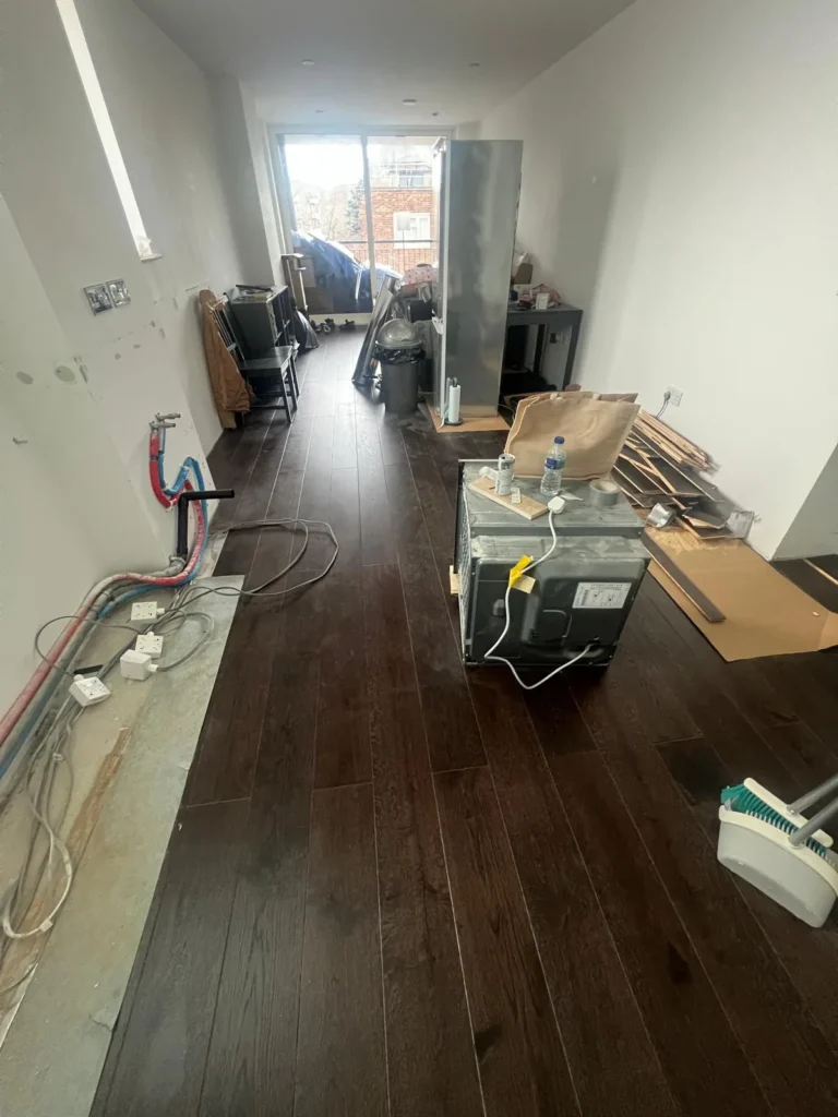 Dark oak plank flooring being laid in an open-plan room