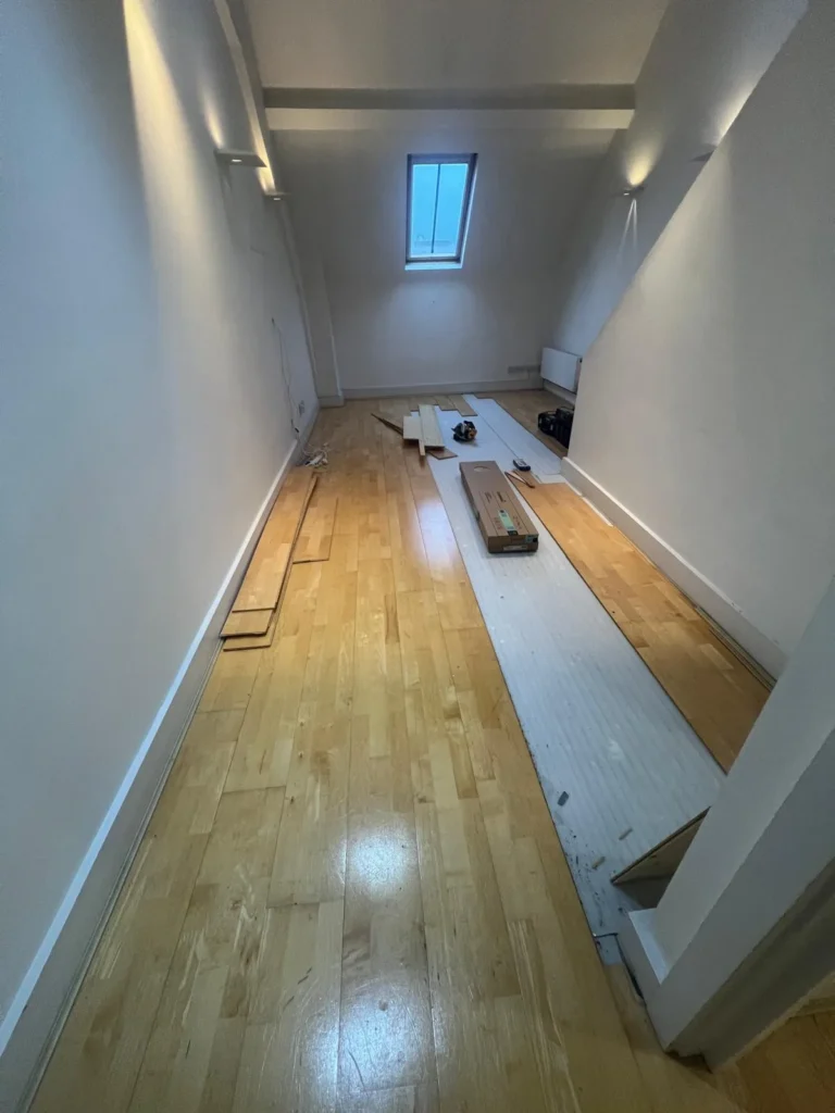 Oak flooring being laid in a long room with a roof light