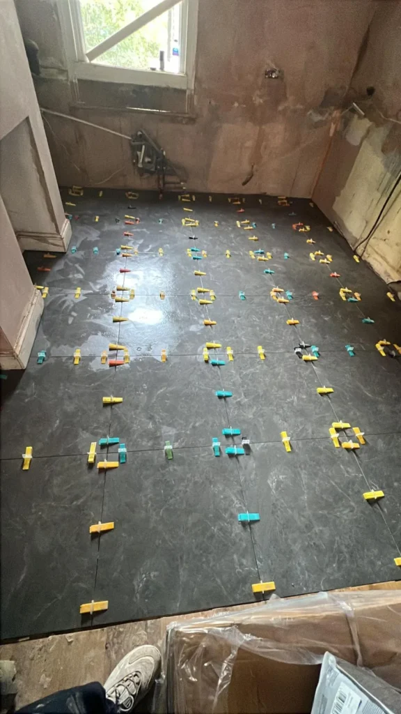 Large dark porcelain floor tiles being laid with levelling clips