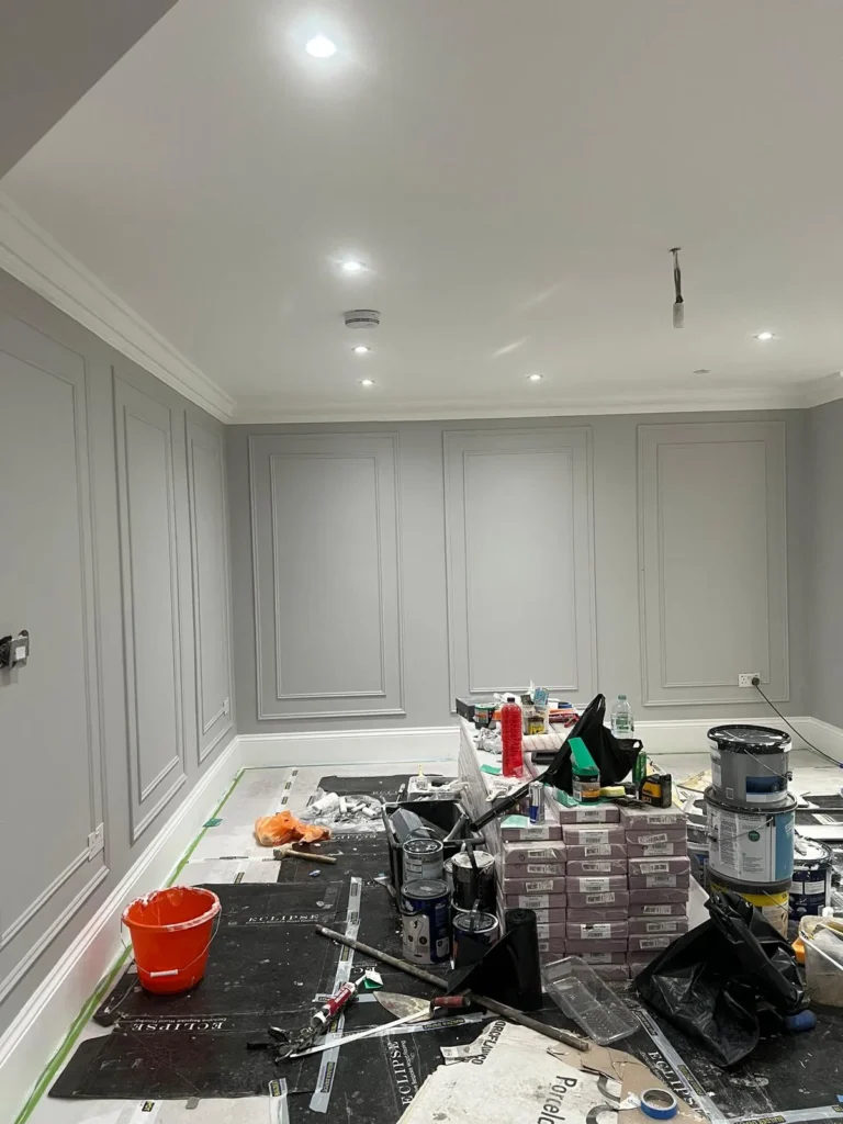 Grey wall panelling and coving being decorated with downlights fitted