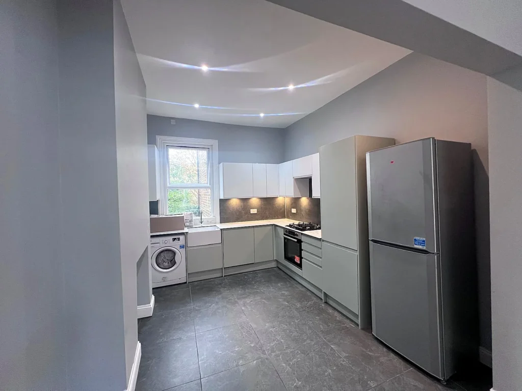 Completed grey handleless kitchen with dark porcelain floor tiles and integrated appliances